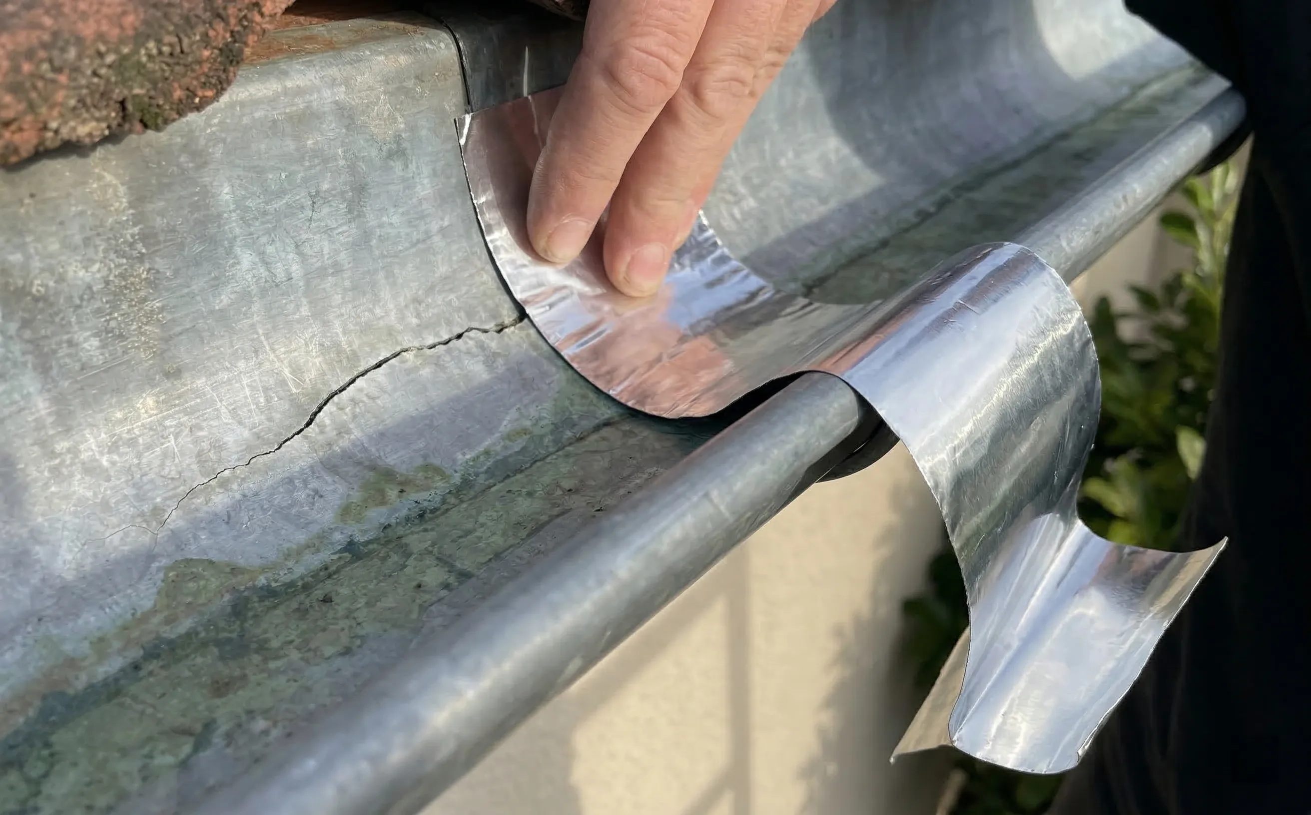 Pose d'une bande bitumineuse autocollante aluminiée sur la face intérieure d'une gouttière zinc