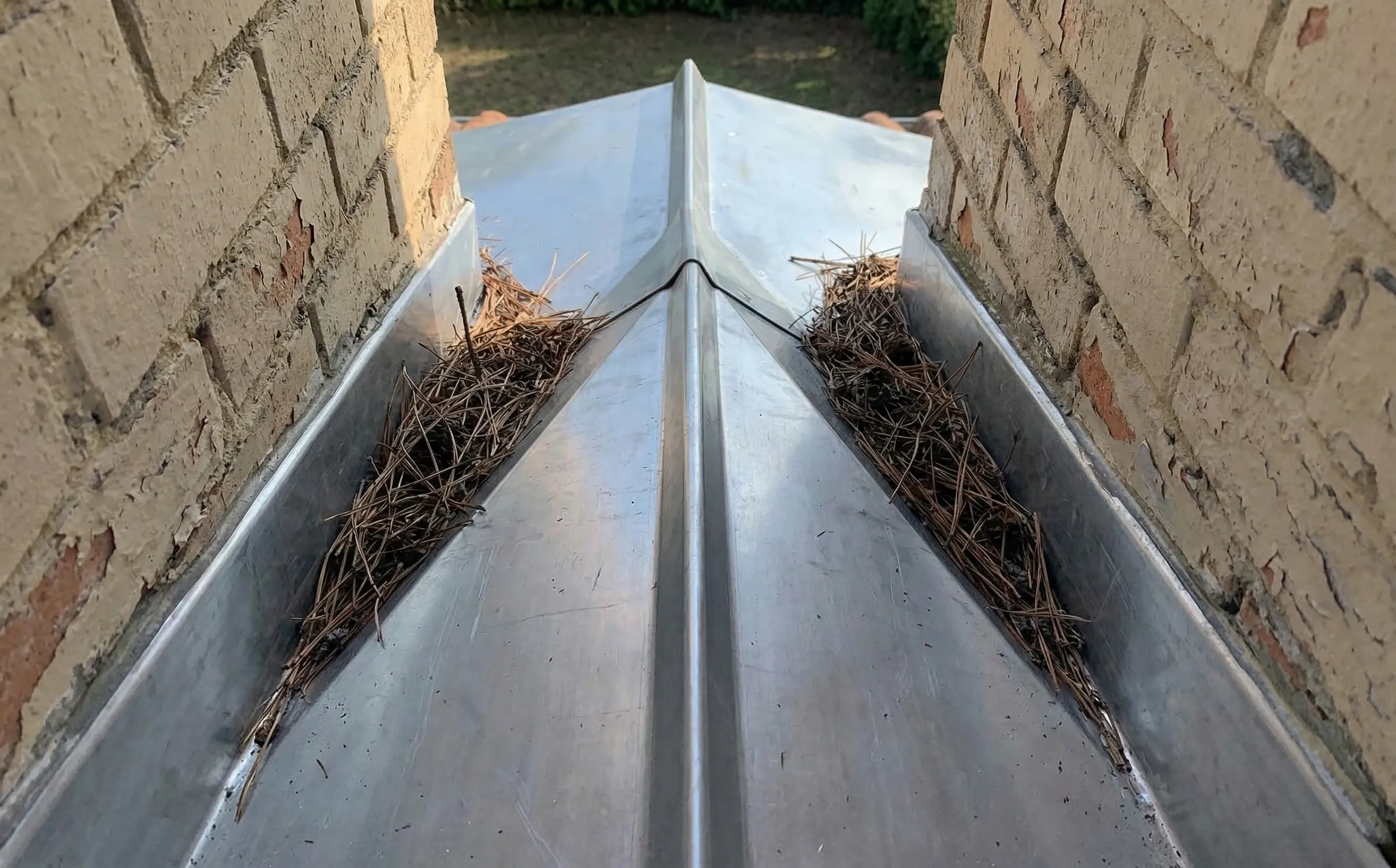 Détail d'une besace en zinc avec son profil en dos d'âne installée en partie haute d'une cheminée