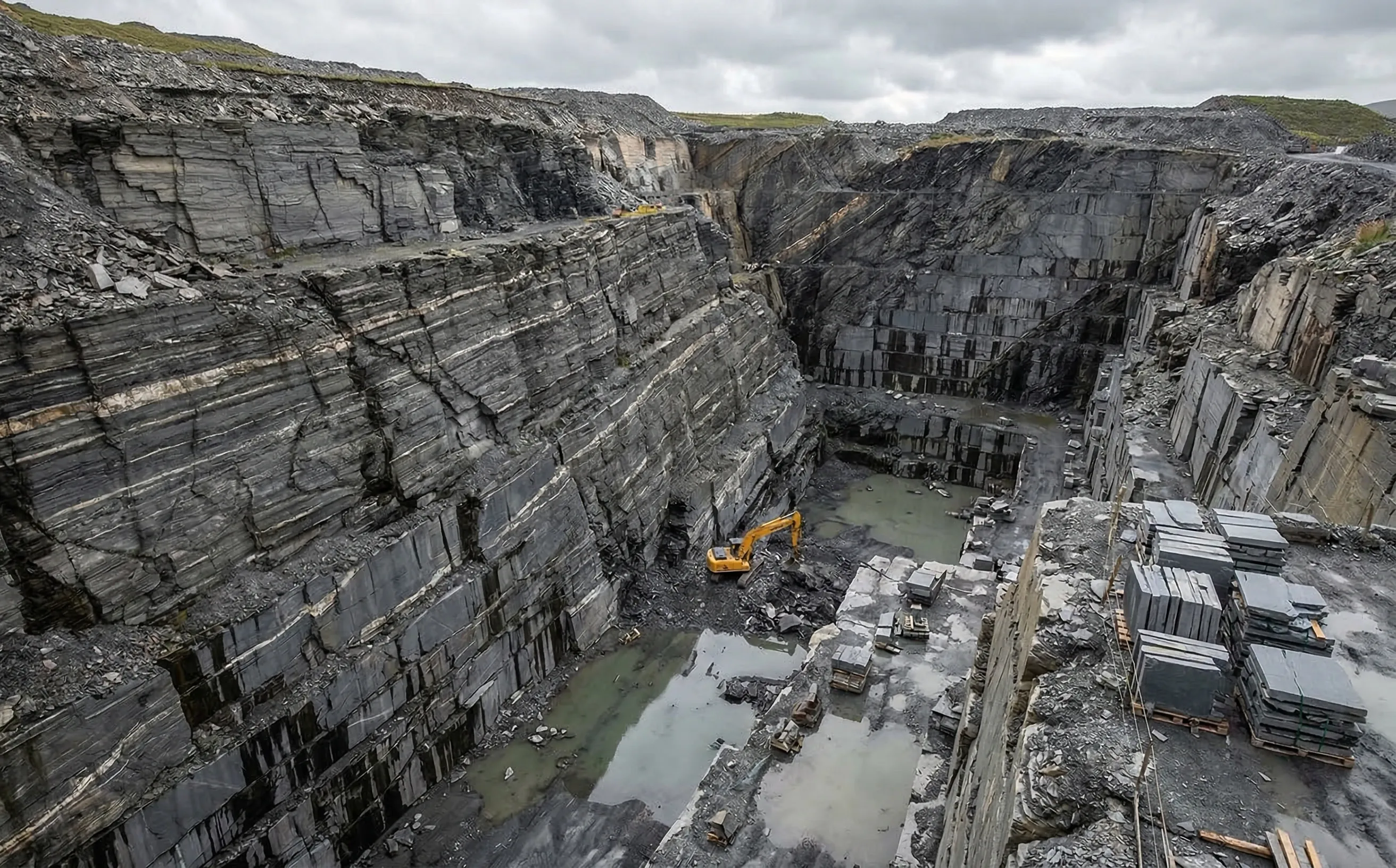 Carrière d'ardoise à ciel ouvert avec strates de schiste gris foncé visibles sur les parois