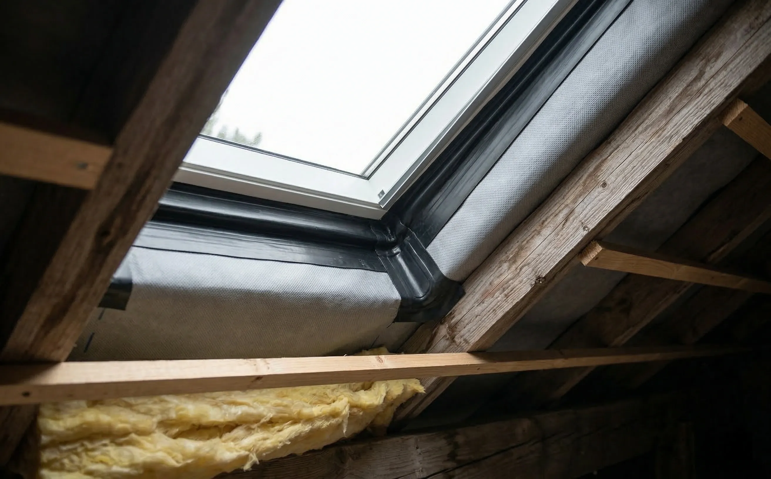 Détail d'un raccord d'écran de sous-toiture autour d'une fenêtre de toit avec manchon adhésif et collerette d'étanchéité