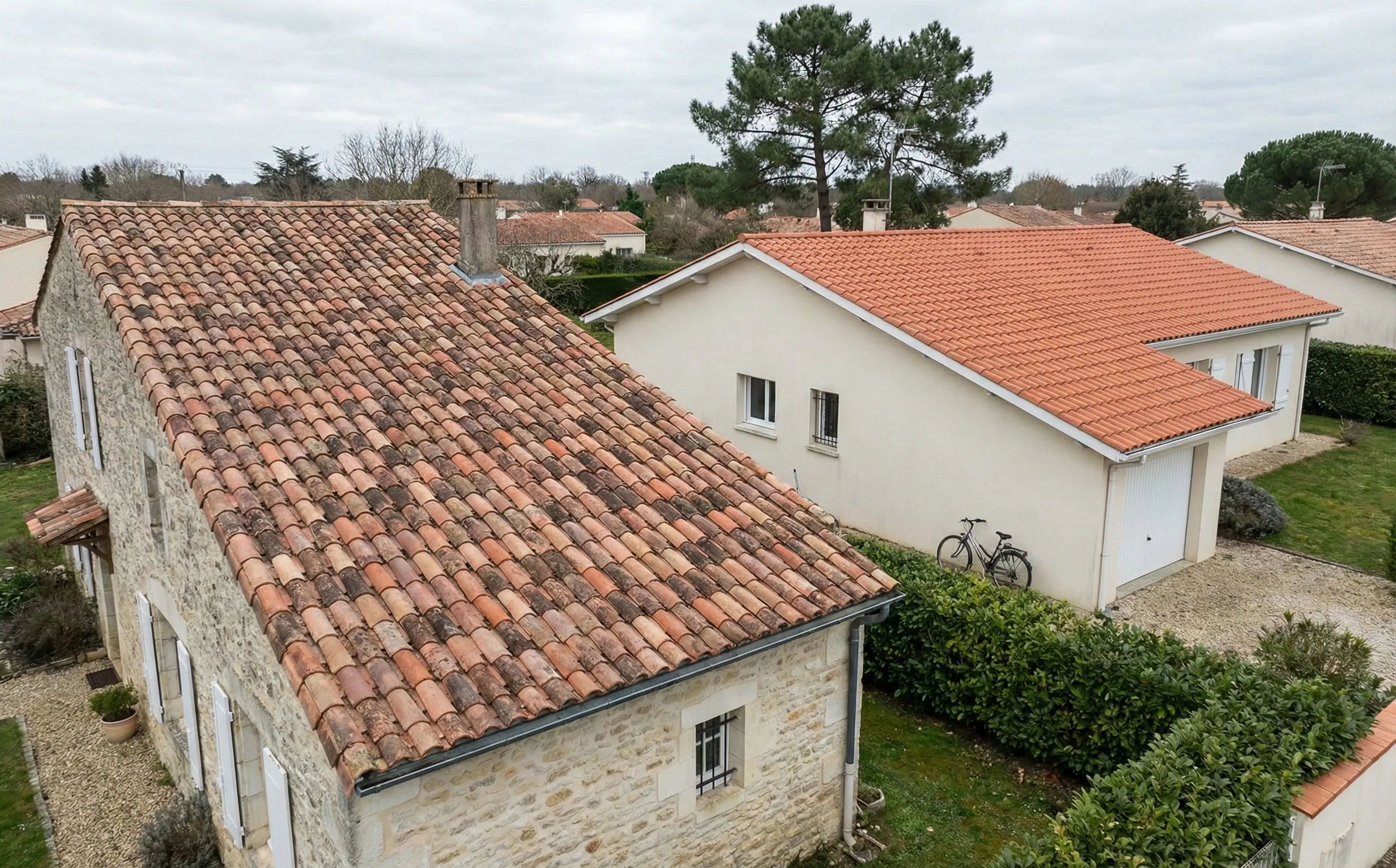 Toitures en tuile canal et tuile mecanique cote a cote dans un quartier residentiel du Sud-Ouest