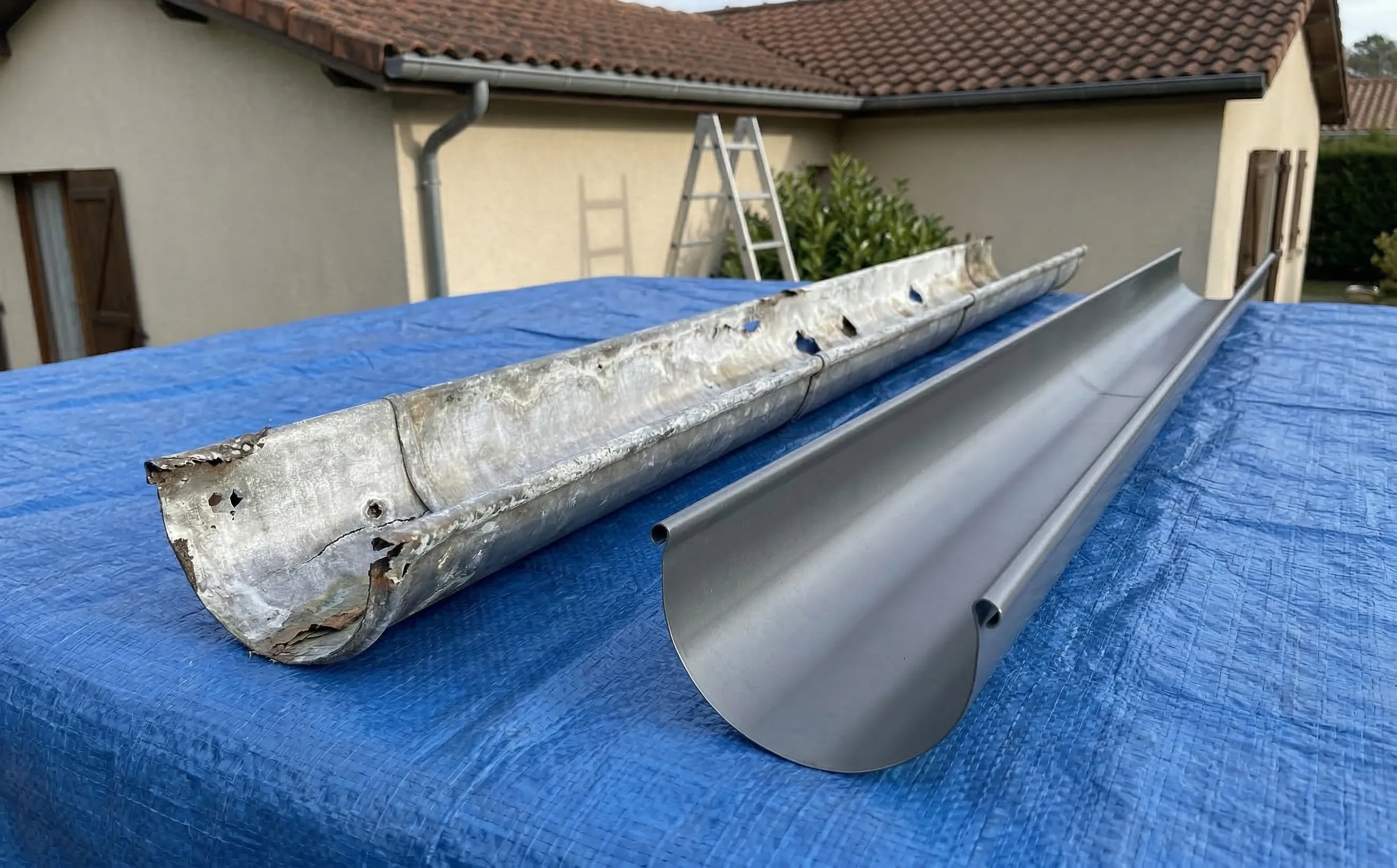 Comparaison entre un tronçon de gouttière zinc corrodé avec perforations et un tronçon neuf en zinc prépatiné