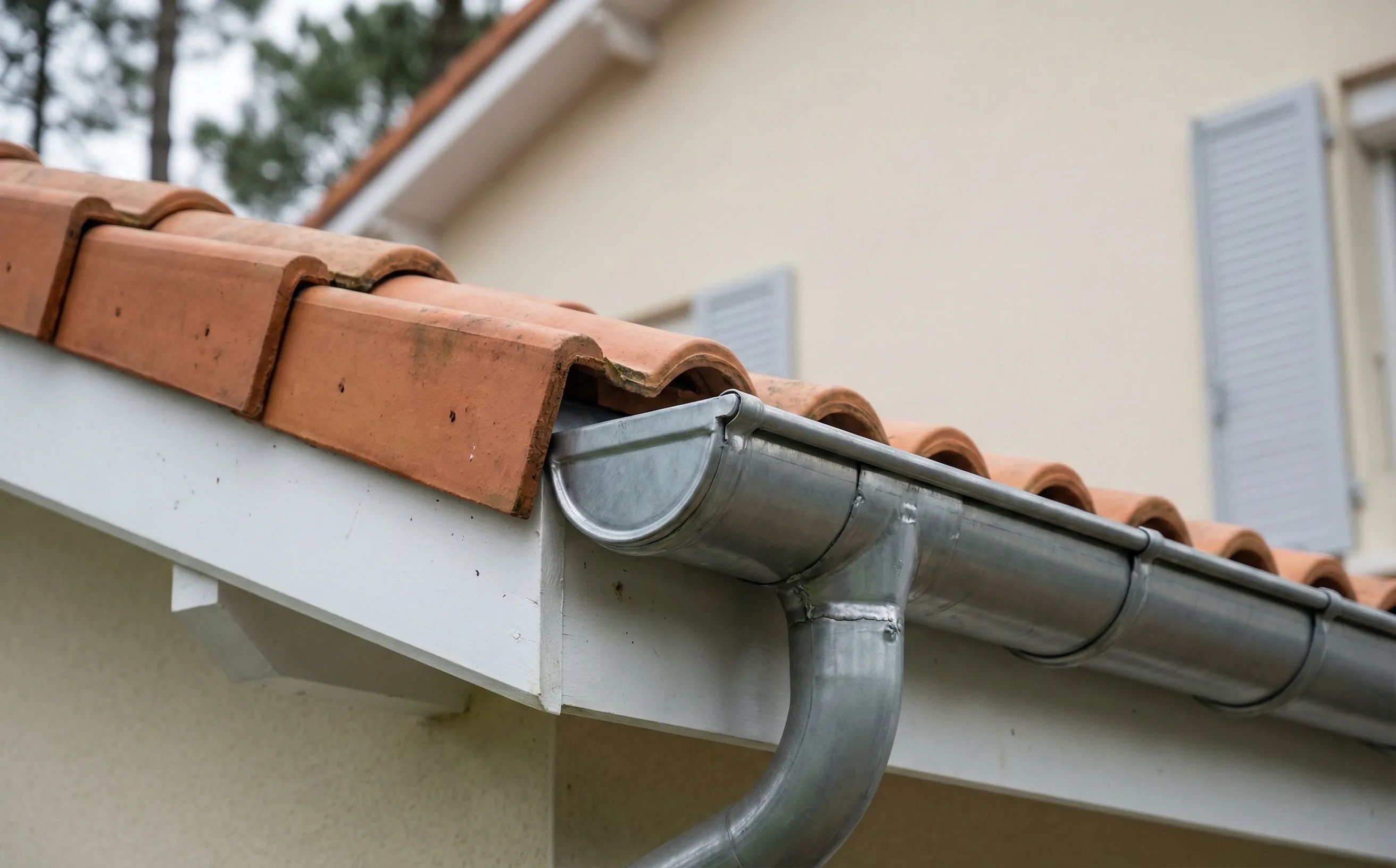 Gouttière zinc neuve posée le long d'une toiture en tuiles terre cuite à Pessac